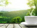 Teacup with steam rising in front of a serene nature background